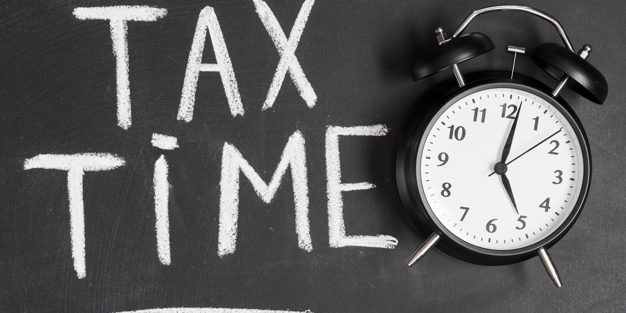 alarm-clock-near-tax-time-word-written-black-backboard-with-chalk_23-2147943569