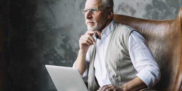 contemplated-elderly-man-sitting-chair-with-laptop-against-grunge-background_23-2147901042