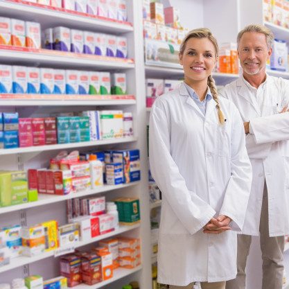 pharmacist-with-his-trainee-standing-smiling-camera_13339-295340