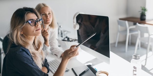 thoughtful-blonde-woman-glasses-holding-pencil-looking-away-during-work-office-indoor-portrait-busy-long-haired-female-accountant-using-computer_197531-3763